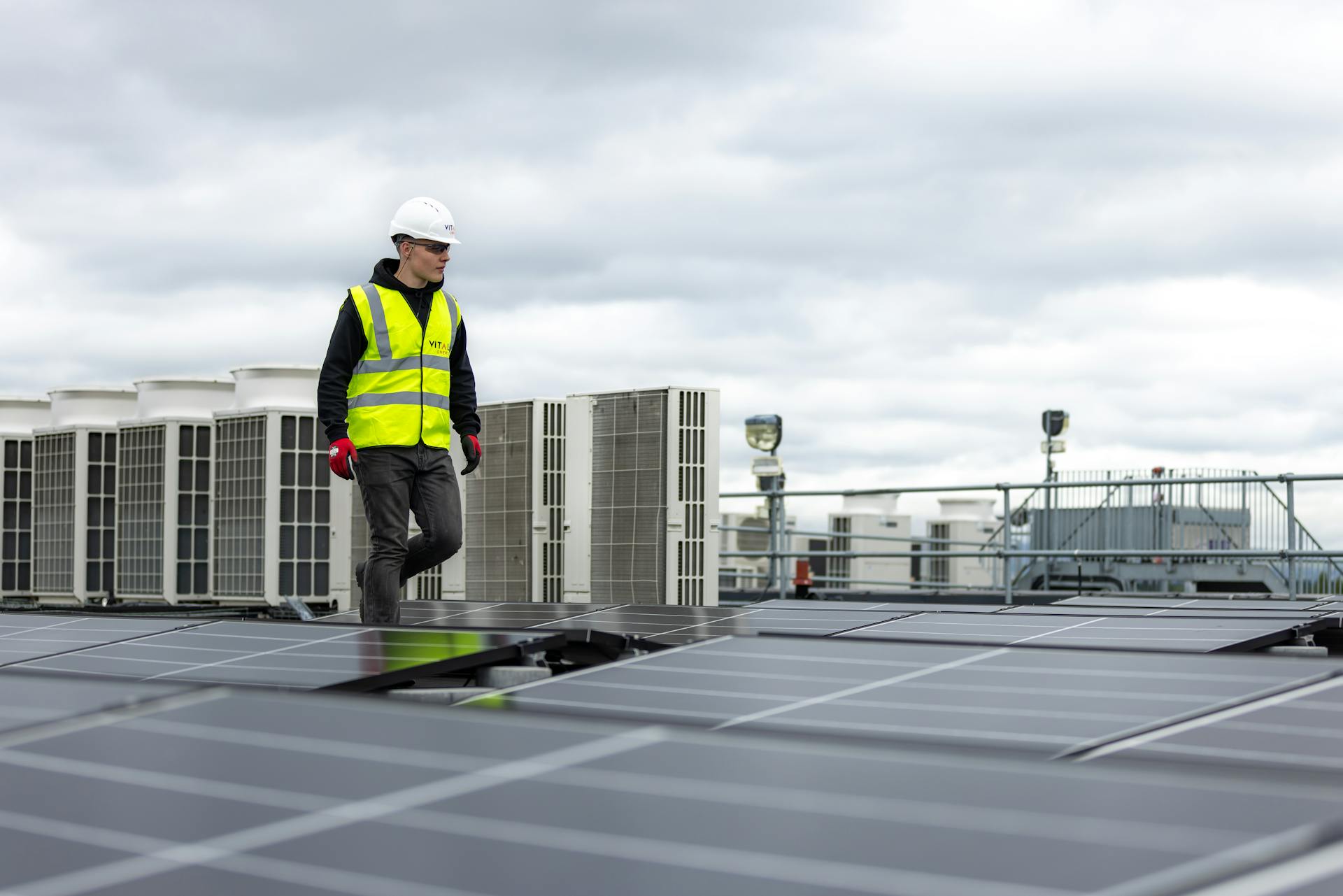 grid engineer walking on a roof filled with solar panels